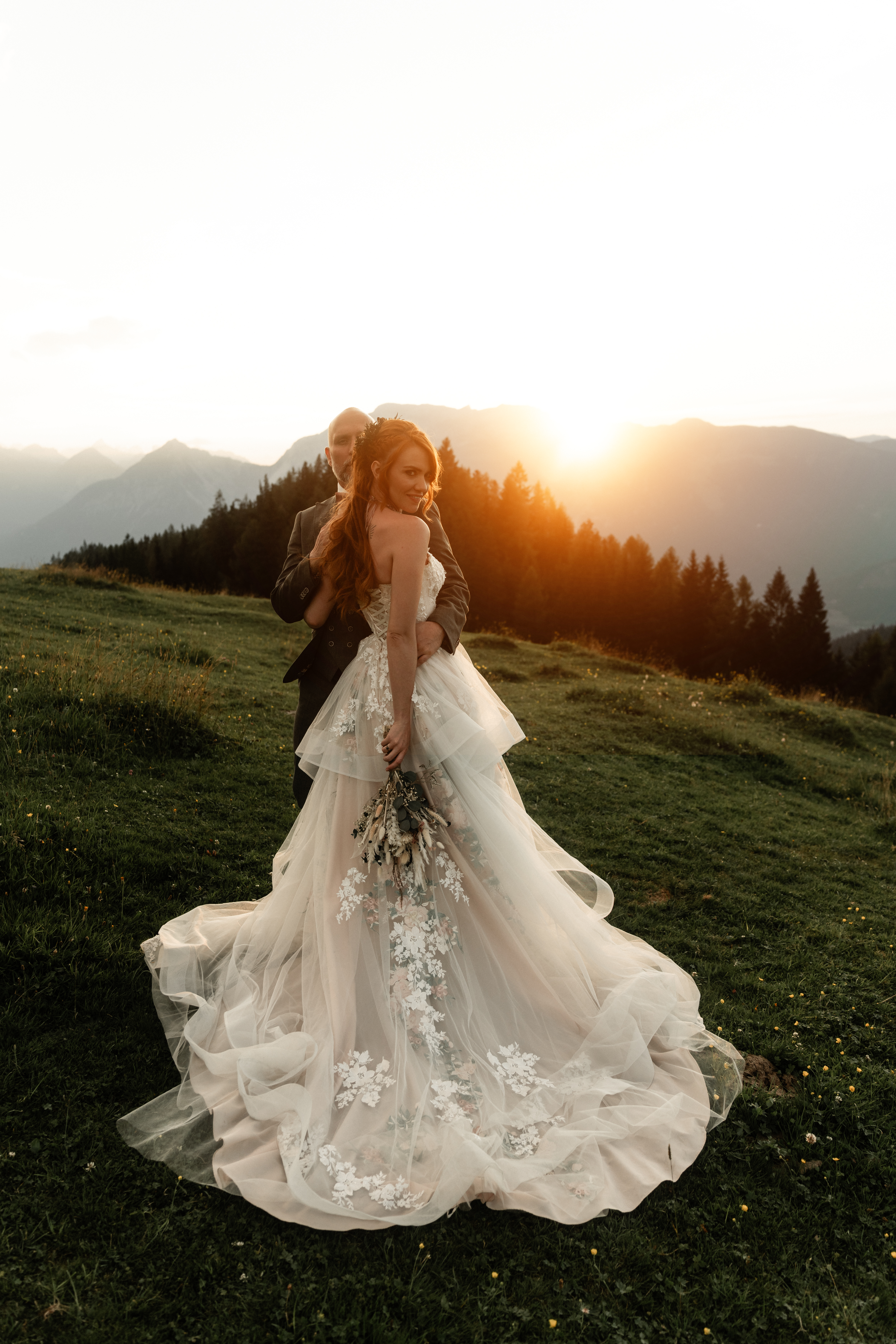 Brautpaar steht im Sonnenuntergang in den Alpen